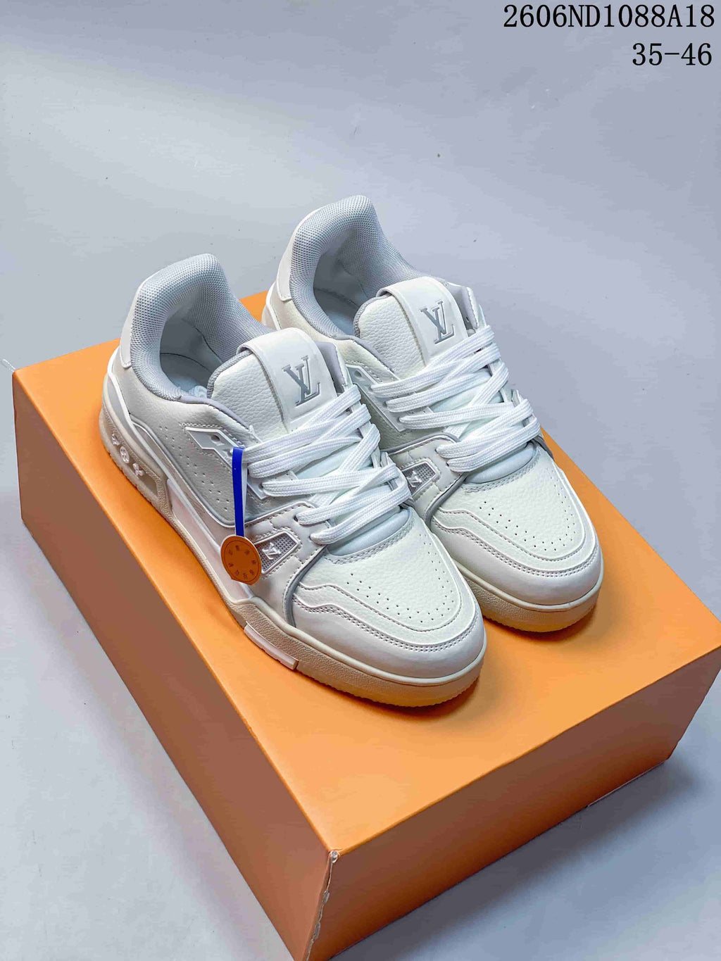 Pair of white Louis Vuitton Trainer low-top sneakers displayed on an orange box