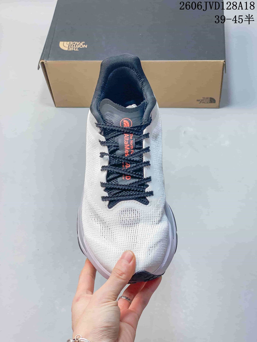 Front view of a white lace-up The North Face running shoe with dark navy laces.