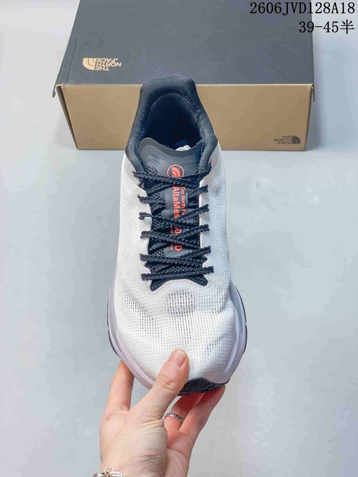 Front view of a white lace-up The North Face running shoe with dark navy laces.