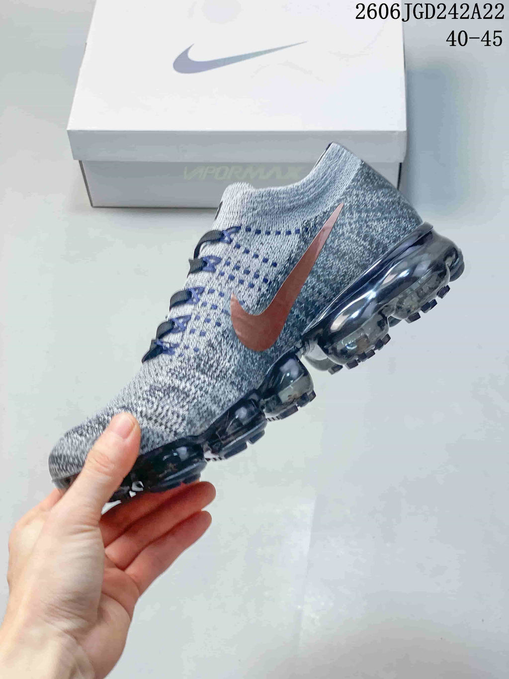 Side view of a gray Nike VaporMax Flyknit sneaker with a copper-tone Swoosh