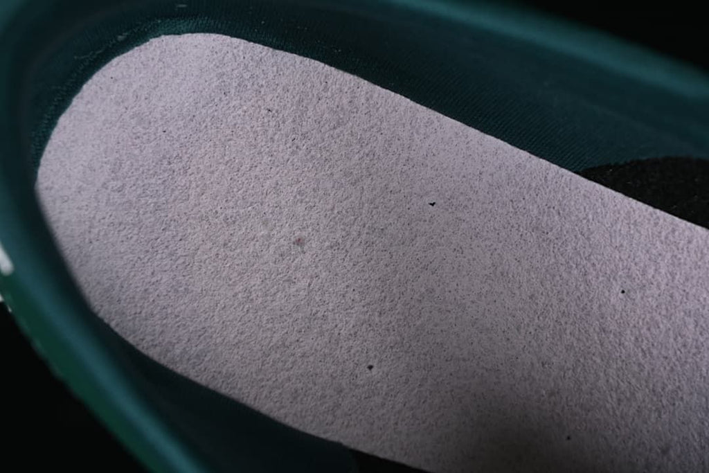 Close-up of the light-colored footbed inside the green sneaker.