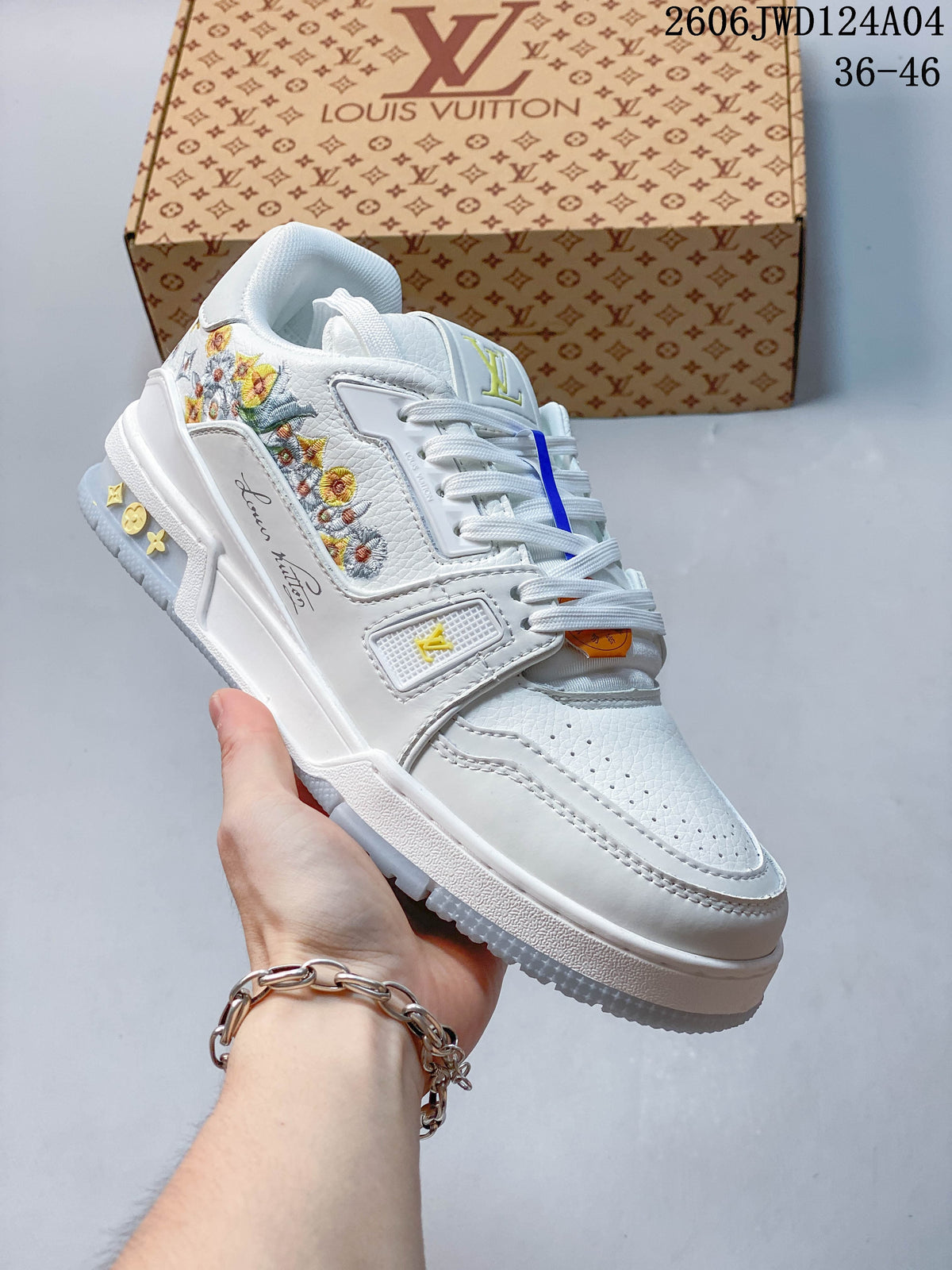 Angled side view of a white low-top sneaker with colorful floral embroidery, yellow accents, and a layered sole.