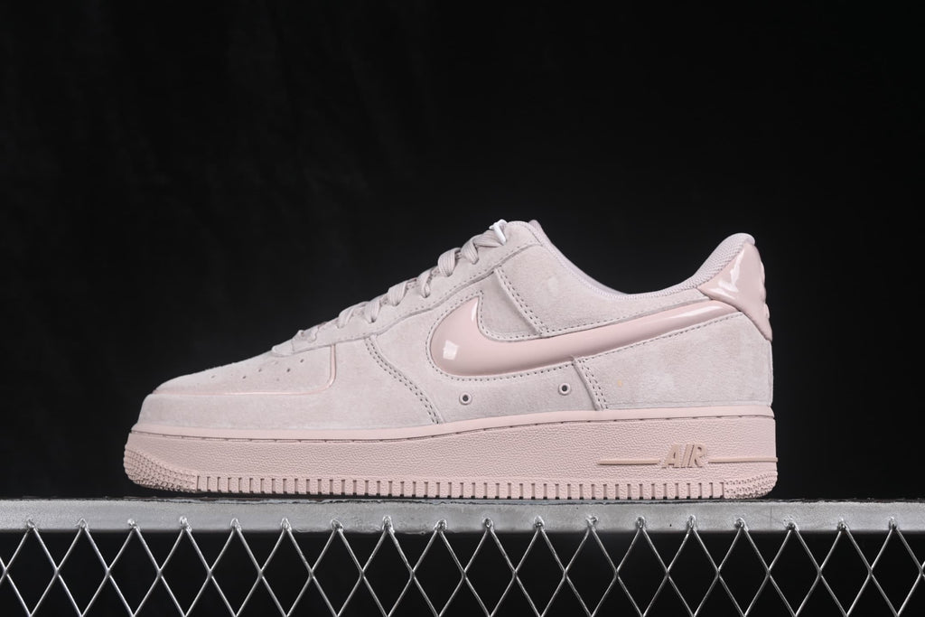 Side profile of pale pink Nike Air Force 1 ’07 Low sneakers with a glossy pink Swoosh and matching sole.