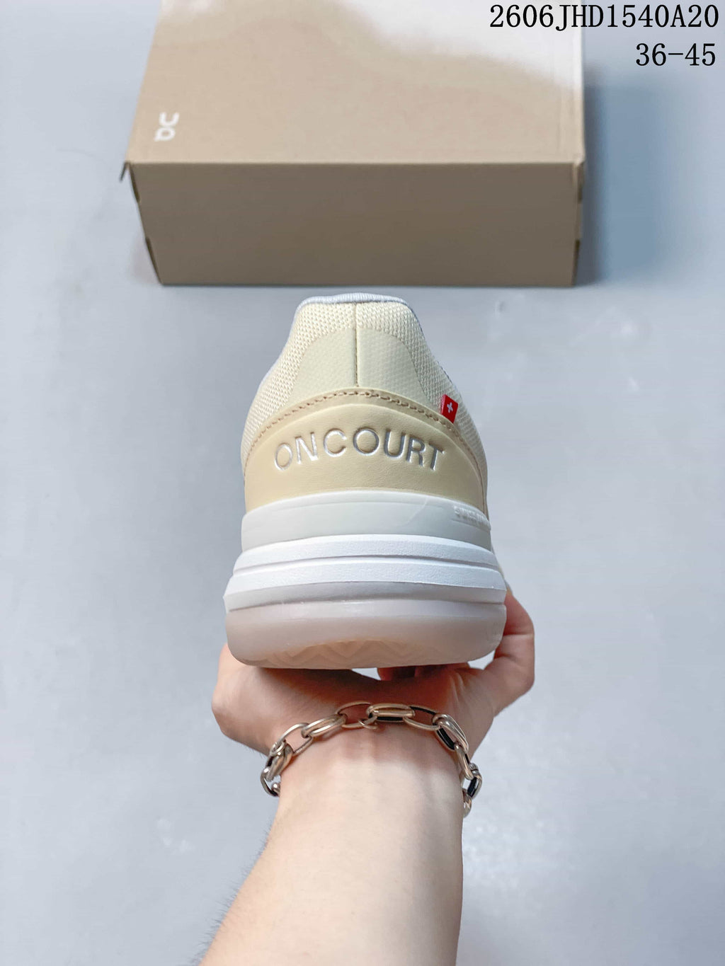 Rear view of the cream On shoe with ON COURT branding