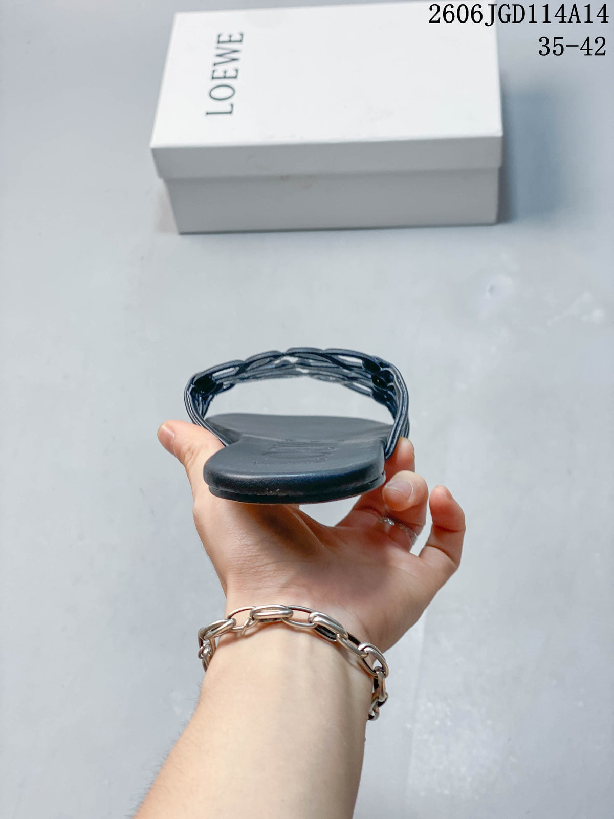 Side profile showing the flat sole and layered sculptural straps of a dark navy slide sandal.