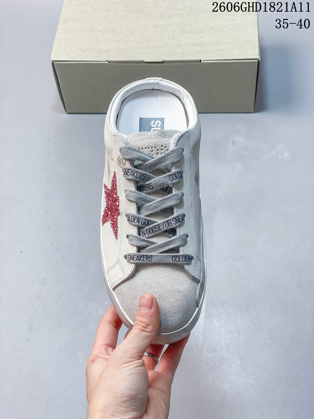 Top view of the sneaker showing gray printed laces, a gray toe panel, and a red glitter star.