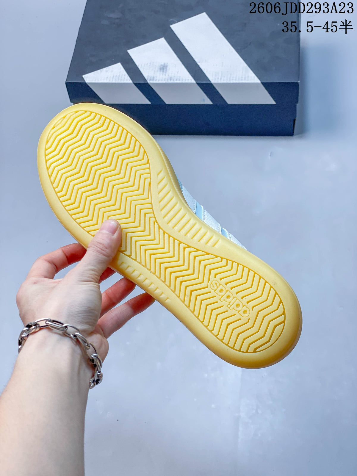 Underside of a sneaker showing a yellow-toned sole with zigzag tread