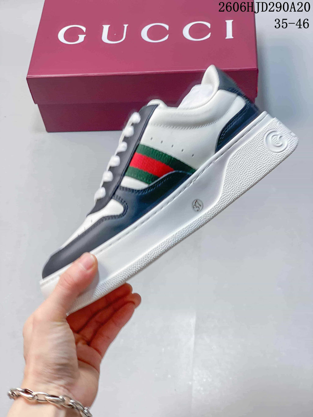 Side view of a white and navy sneaker with green-and-red stripe detail