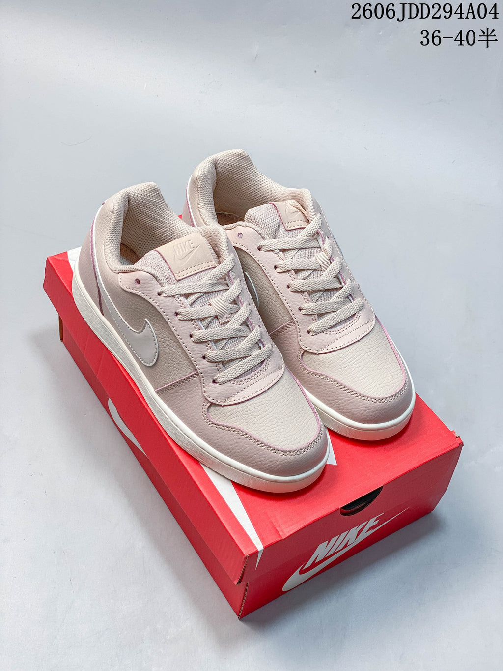 Pale pink Nike Ebernon Low sneakers on a red Nike shoe box; image text shows size ranges 36–40.5 and 36–45.5.