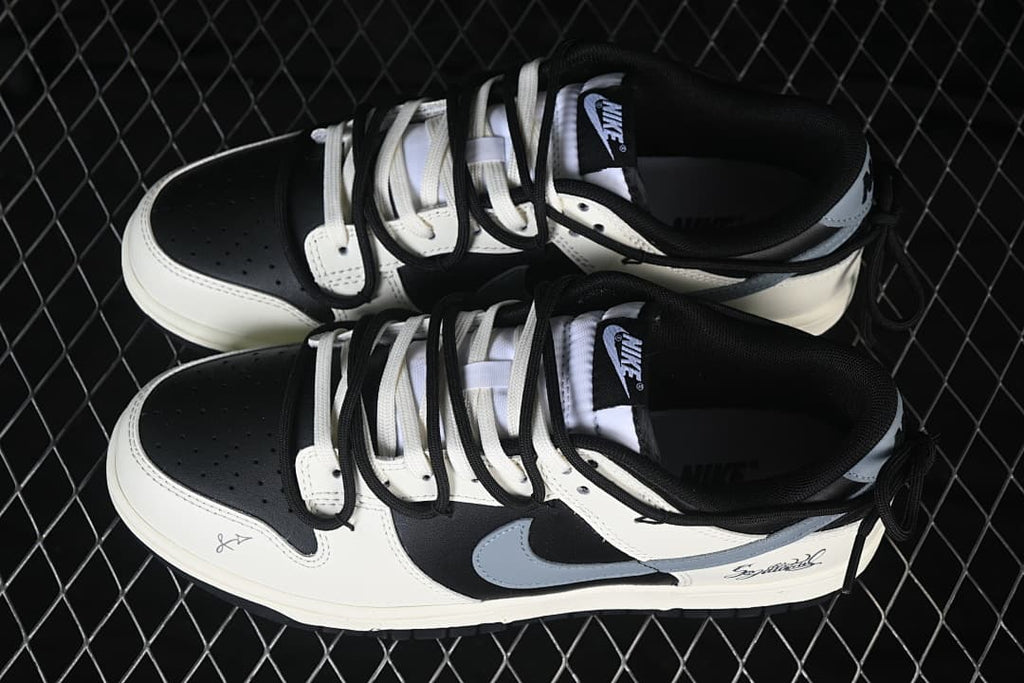 Pair of black and white Nike SB Dunk Low sneakers with layered black and white laces and gray side Swooshes