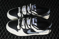 Pair of black and white Nike SB Dunk Low sneakers with layered black and white laces and gray side Swooshes