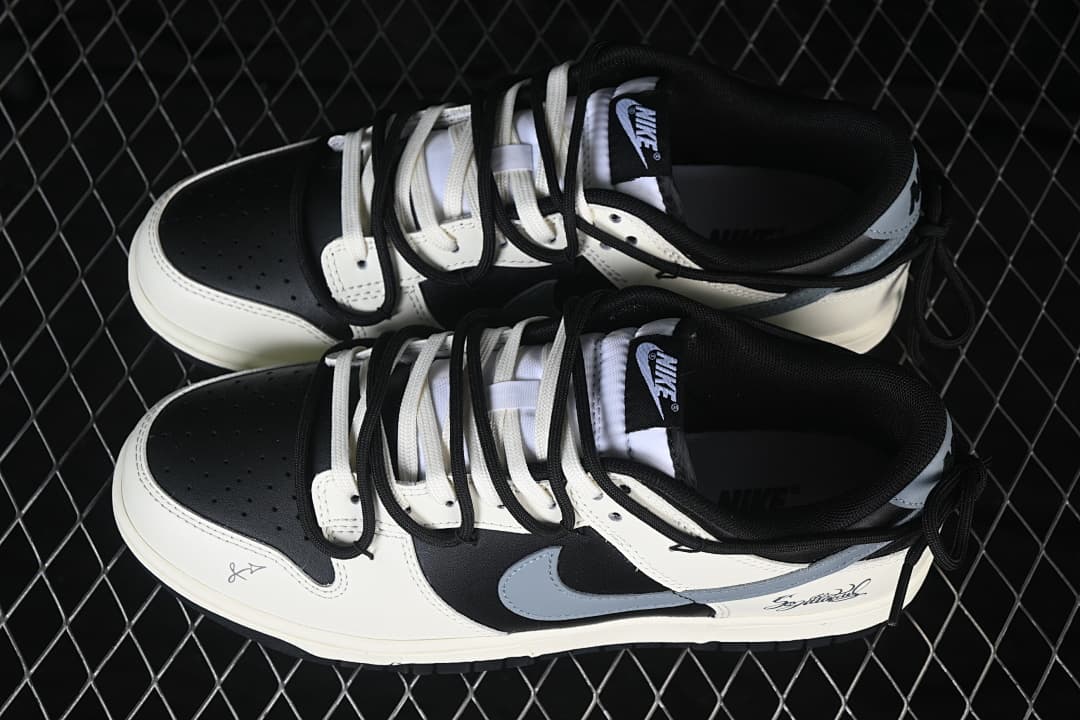 Pair of black and white Nike SB Dunk Low sneakers with layered black and white laces and gray side Swooshes