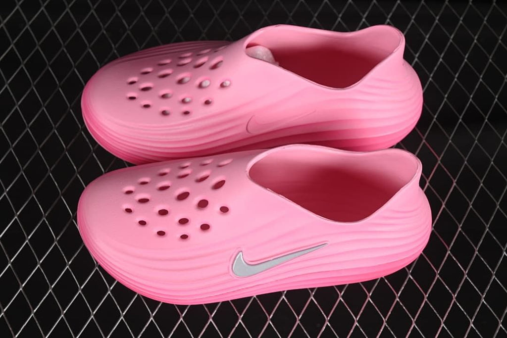 Pair of bright pink perforated clogs with sculpted side ridges and Swoosh accents.