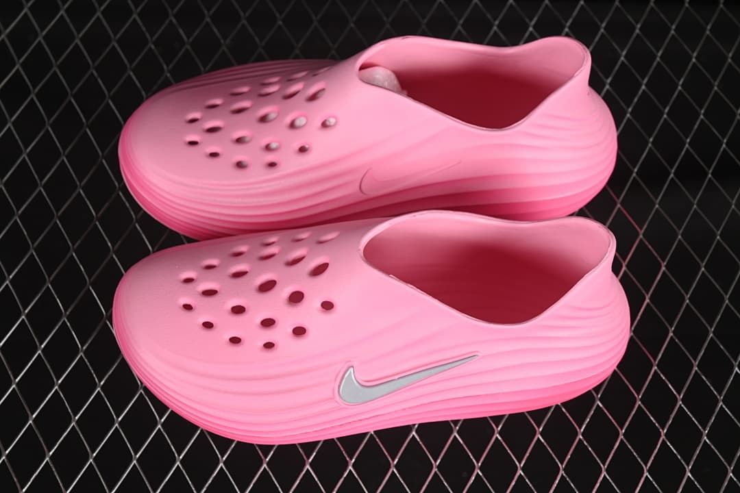 Pair of bright pink perforated clogs with sculpted side ridges and Swoosh accents.