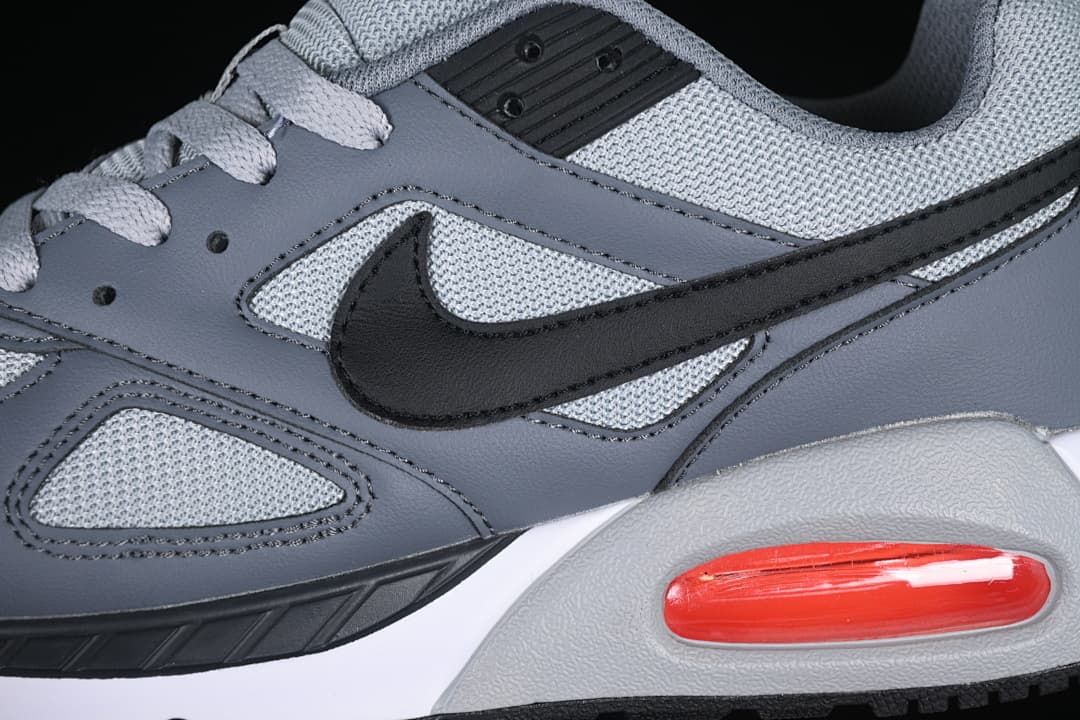 Close-up of the black Swoosh, grey overlays, and red heel Air unit