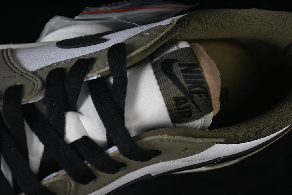 Close-up of the tongue and interior of the olive and white sneaker