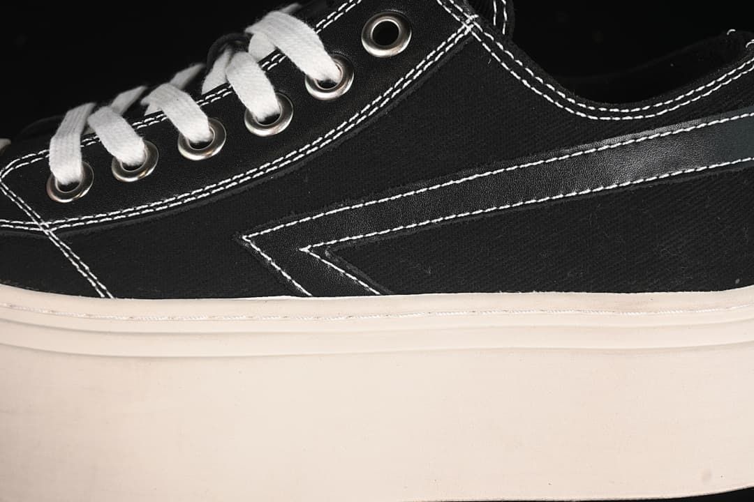 Close-up of white laces, metal eyelets, contrast stitching, and the side panel.