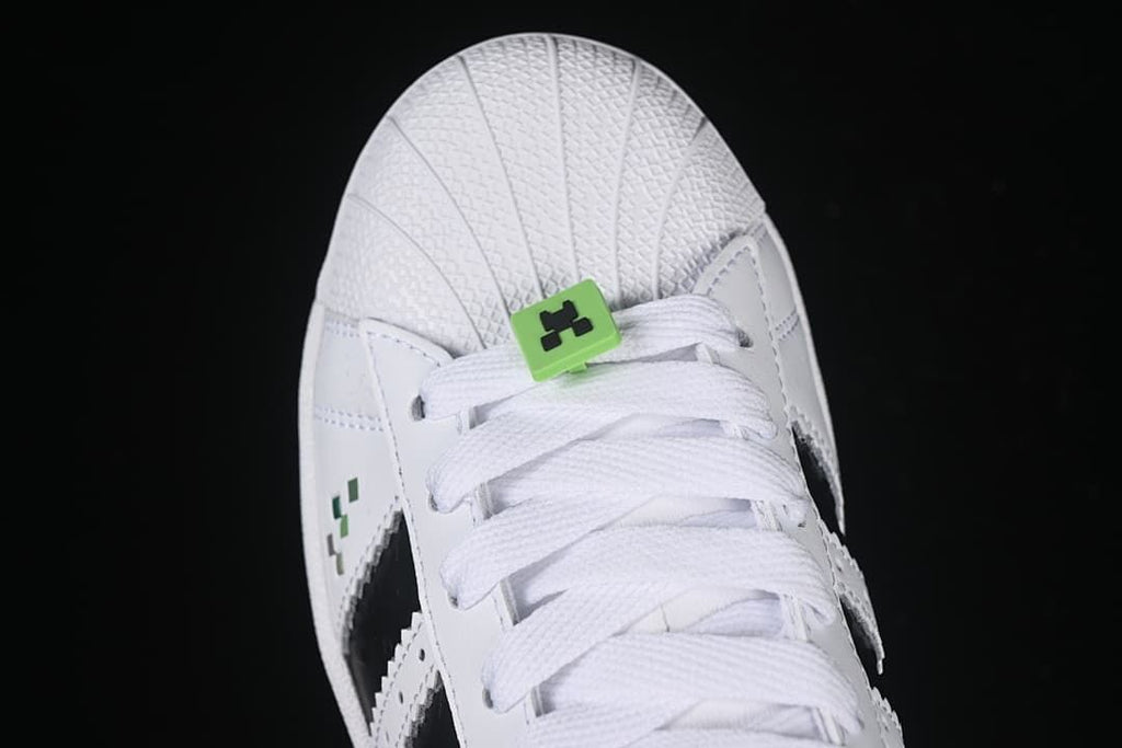 Top view of the shell toe, white laces, and green lace accessory