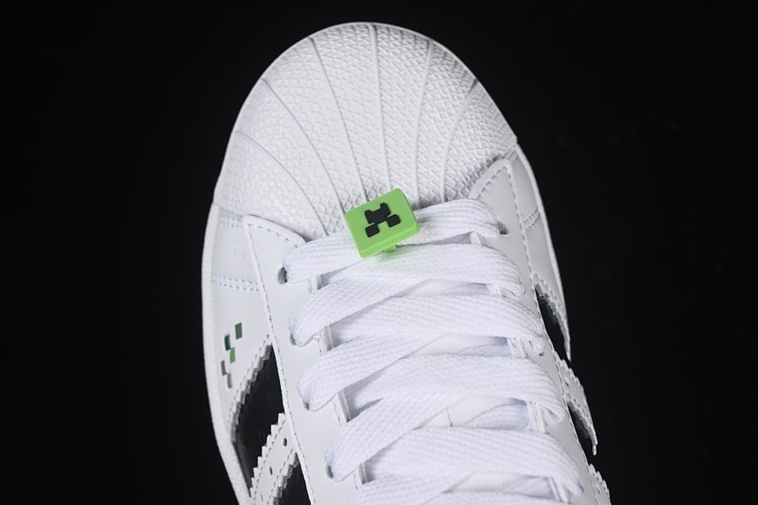 Top view of the shell toe, white laces, and green lace accessory