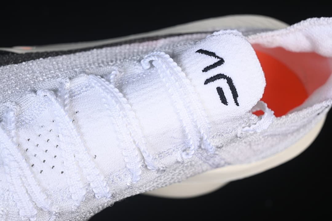 Close-up of white laces, tongue and orange lining