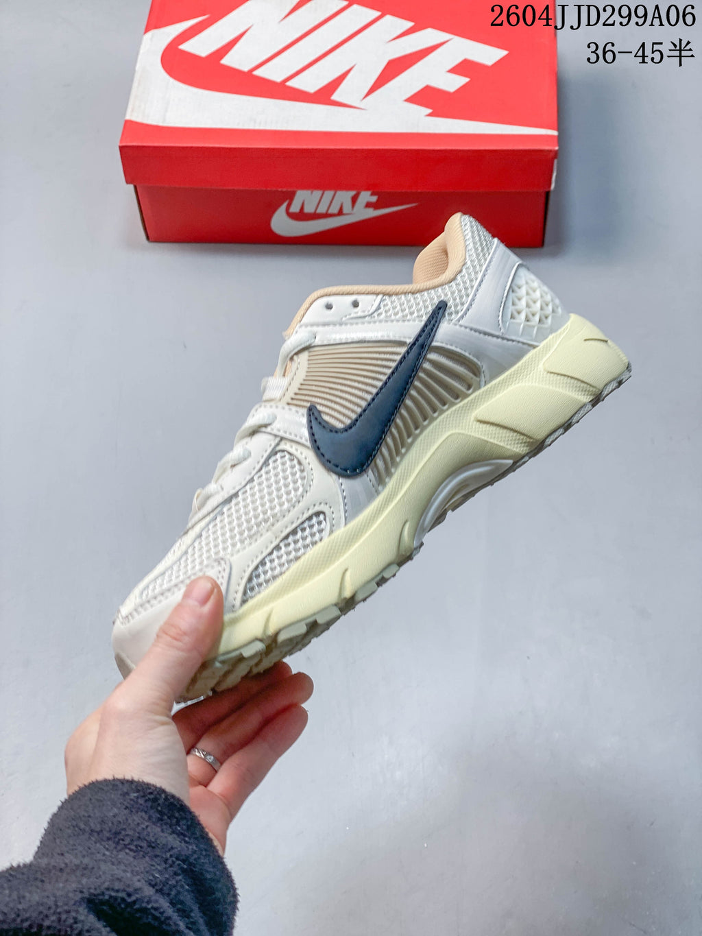 Side view of a light-colored Nike Zoom Vomero 5 sneaker with mesh panels and a dark Swoosh.