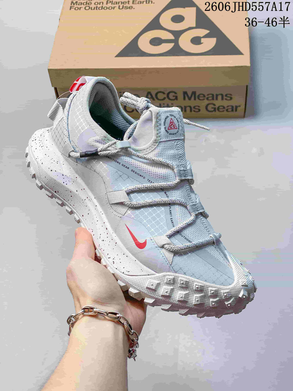 Nike ACG Mountain Fly sneaker in white and light gray with a red accent and lugged outsole.