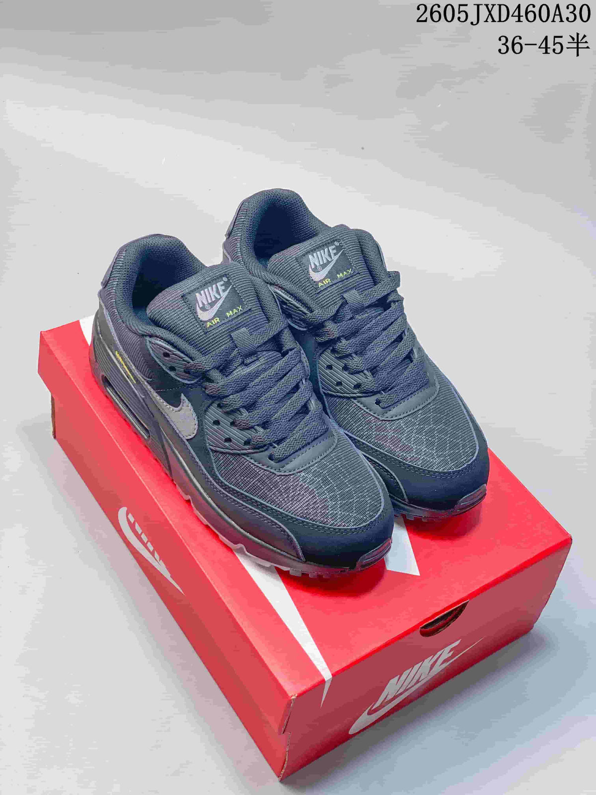 Pair of charcoal gray Nike Air Max 90 sneakers on a red shoe box