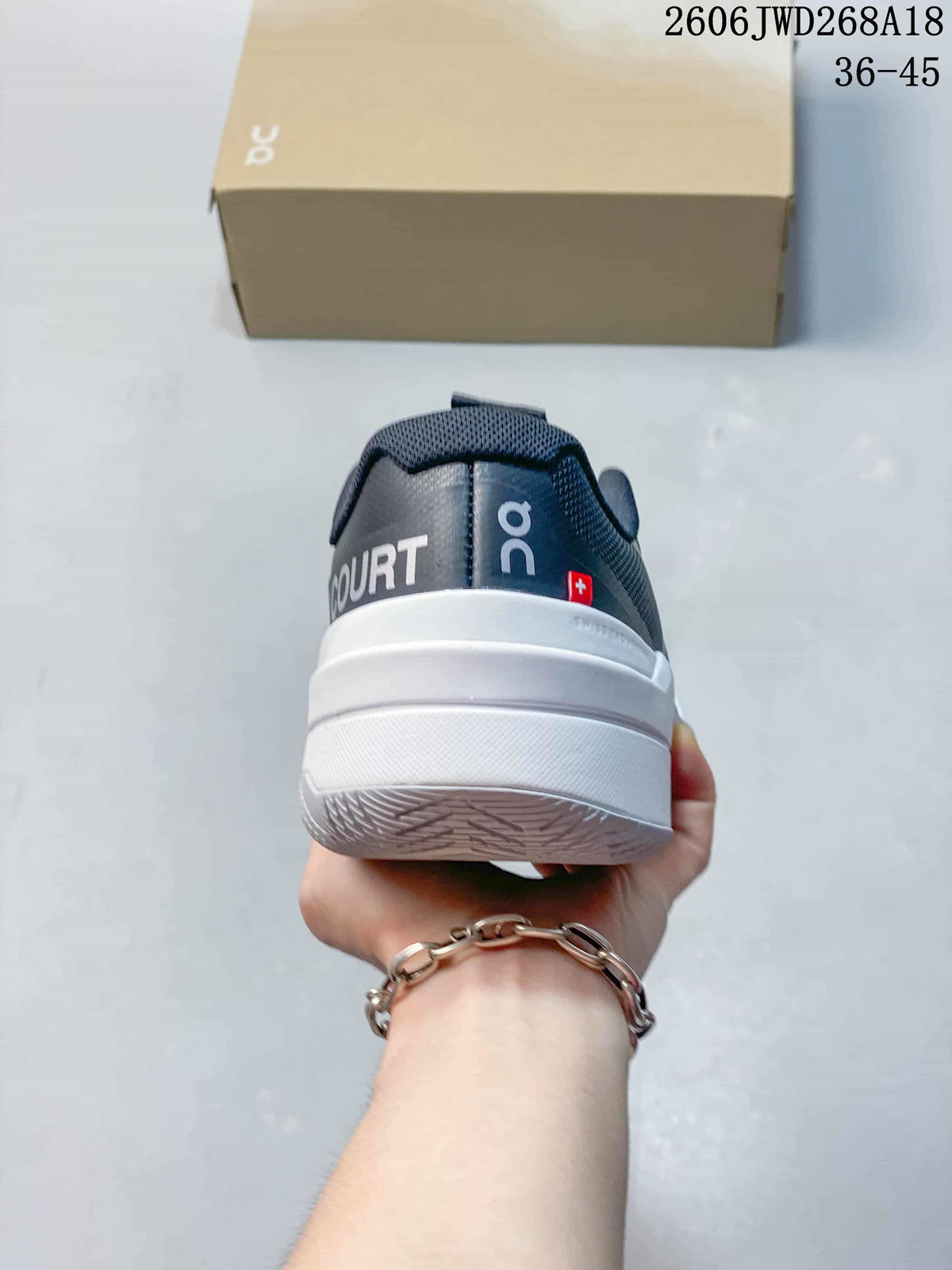 Rear view showing the heel branding and white midsole of a gray tennis shoe.