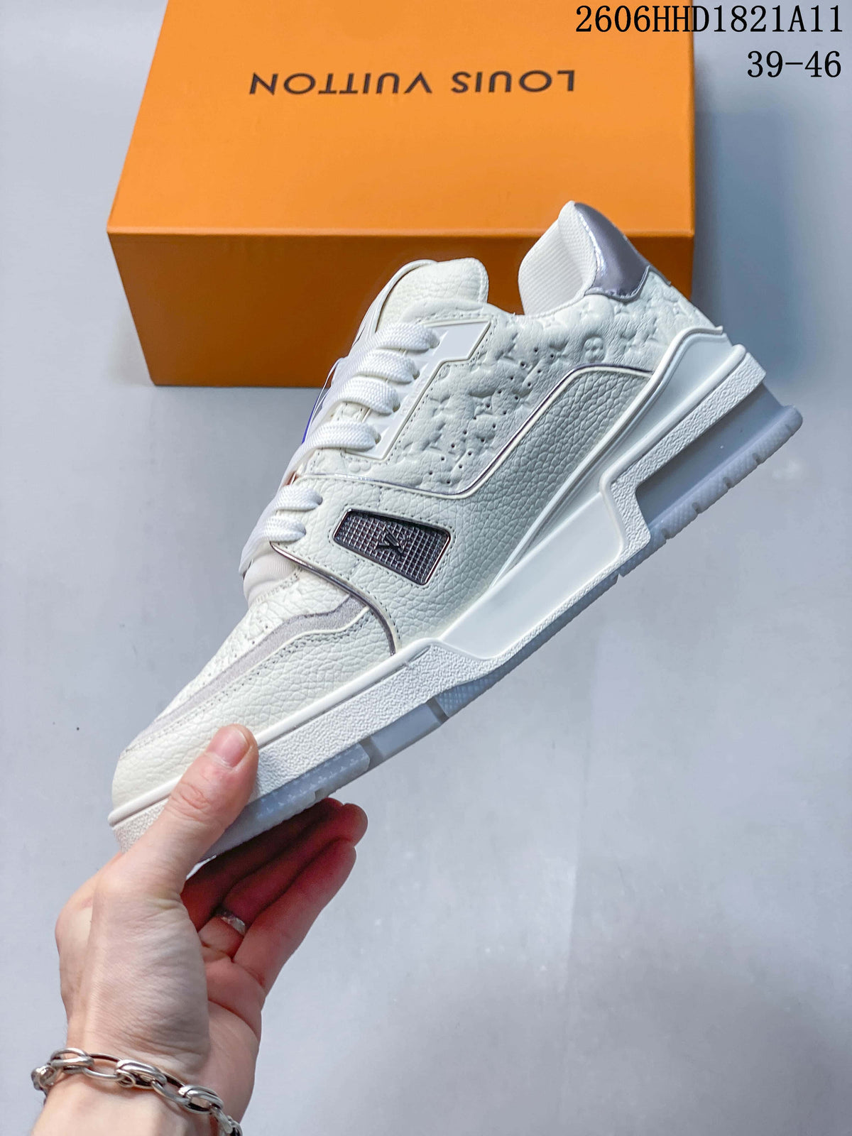 Side view of the white Trainer sneaker with textured panels and metallic-tone accents.