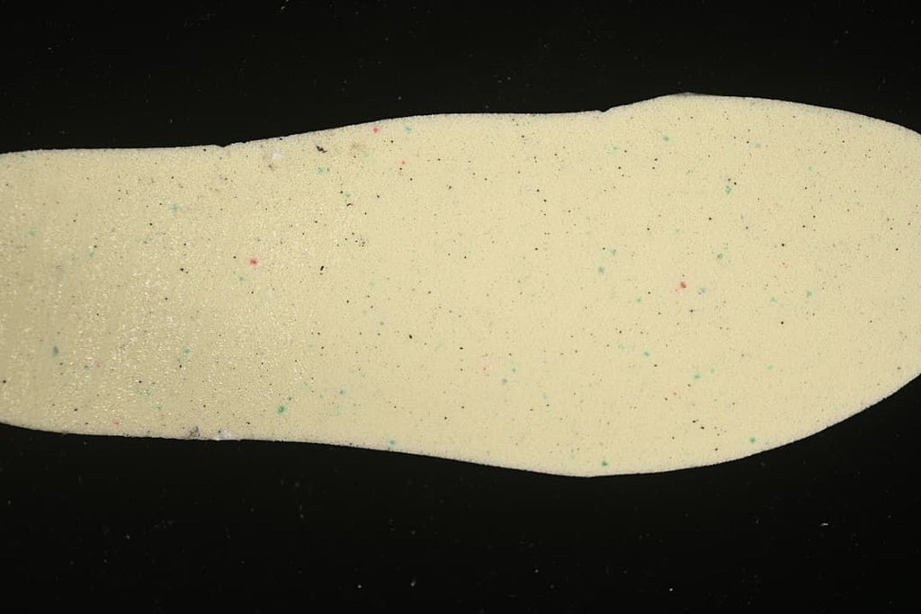 Light-colored shoe insole photographed against a dark background.