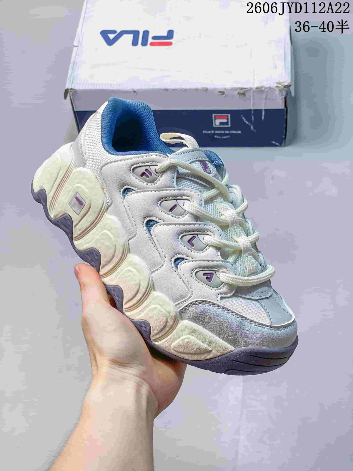 Close angled view of a white and blue FILA sneaker with a chunky sculpted sole