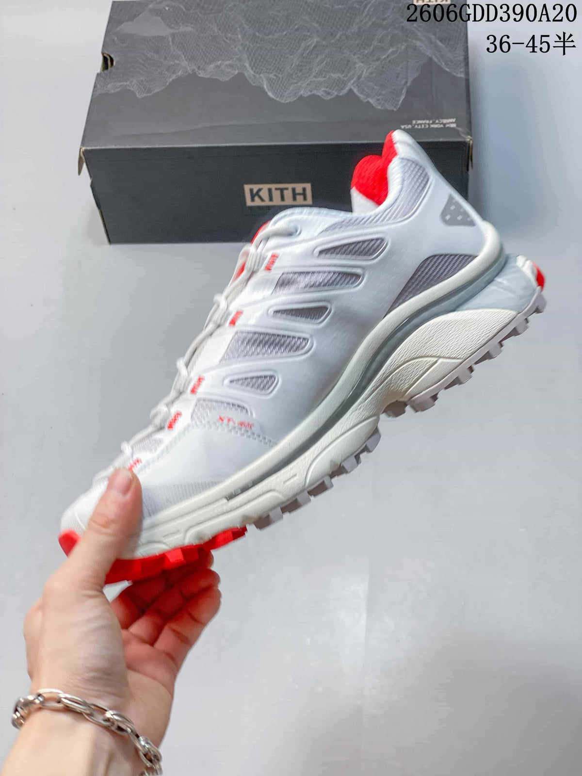 Side view of the white and gray trail shoe with red accents and a lugged outsole