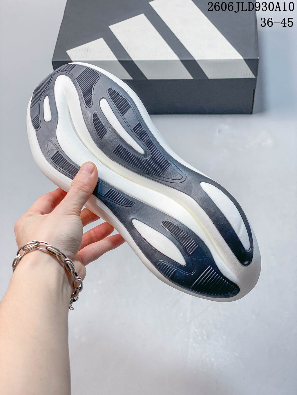 Underside of the white adidas Hyperboost sneaker showing its patterned gray and dark outsole.