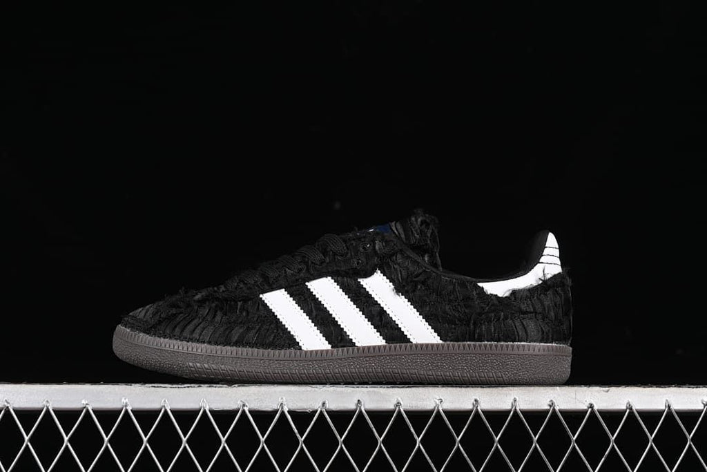 Side view of a black adidas Samba OG sneaker with white stripes and a dark outsole