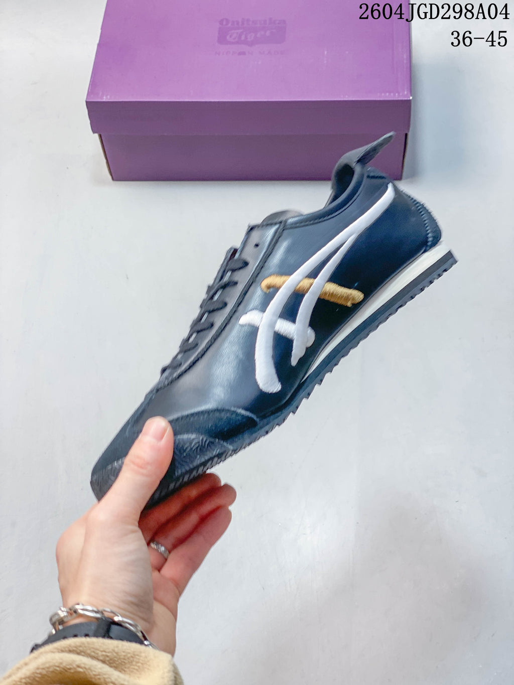 Side profile of a navy Onitsuka Tiger Mexico 66 Deluxe sneaker with white and gold stripes