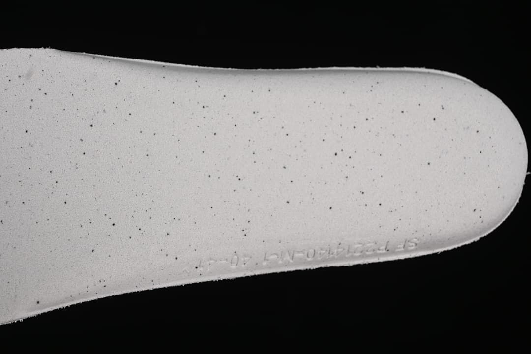 Close-up of a light-colored shoe insert with scattered dark speckles.