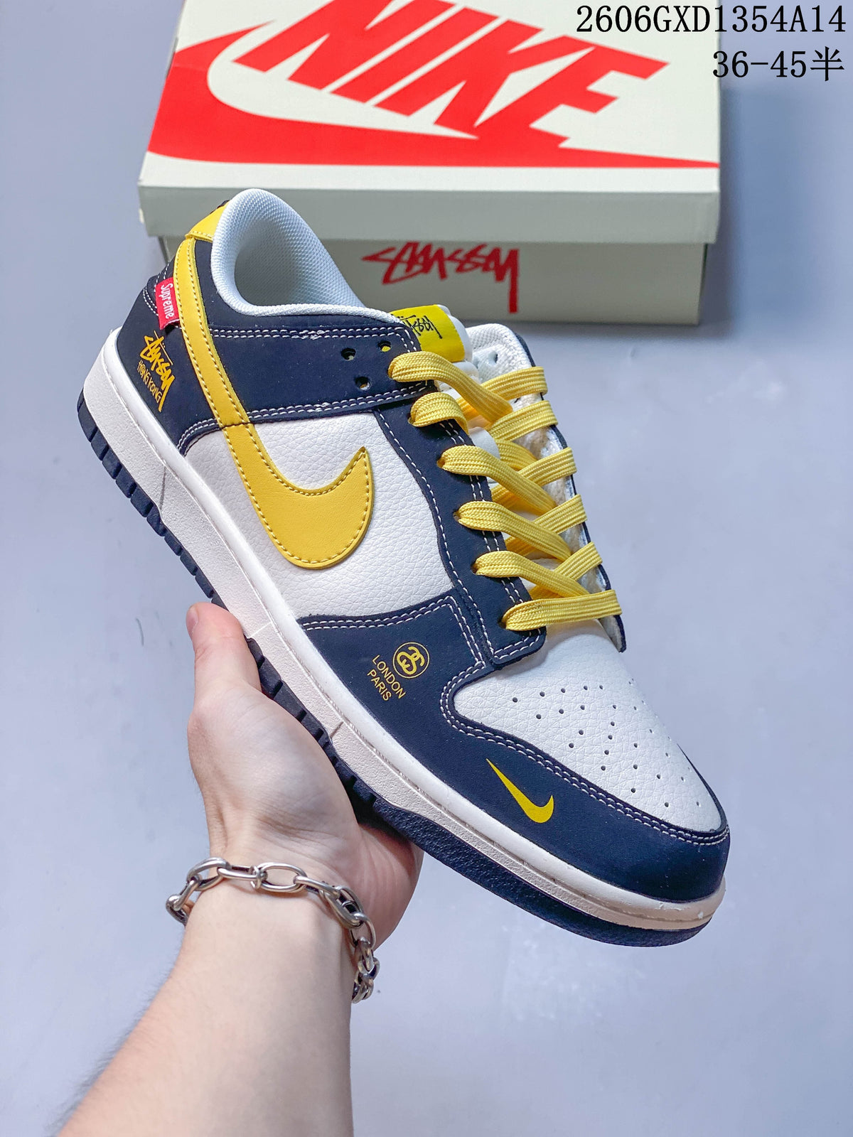 Side view of a navy and white Nike Dunk Low sneaker with yellow accents