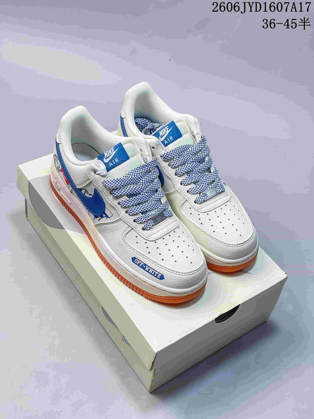 Pair of white low-top sneakers with blue accents, patterned laces and gum-colored soles on a shoe box