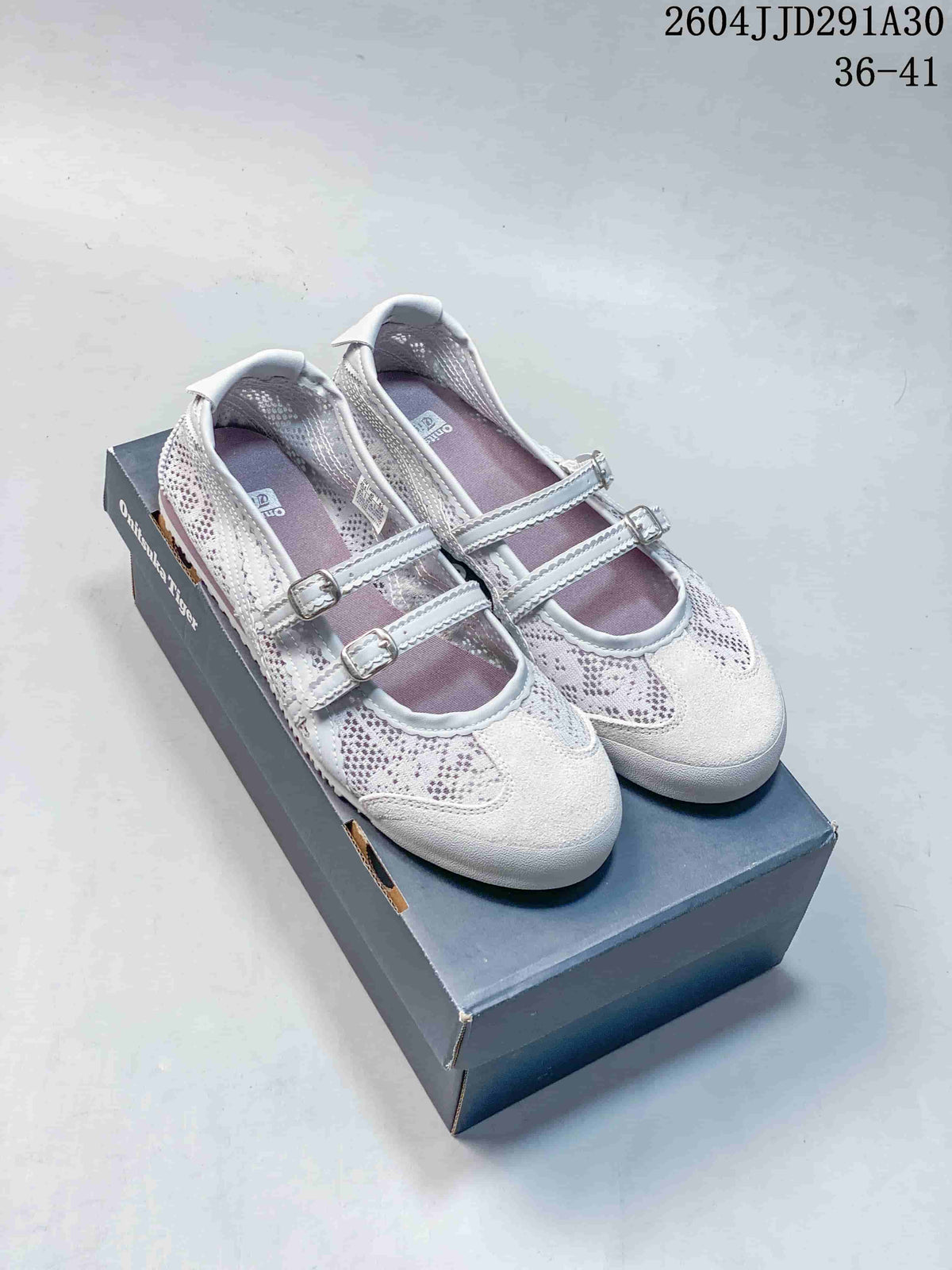 Pair of pale Mary Jane-style shoes with two buckle straps on a box