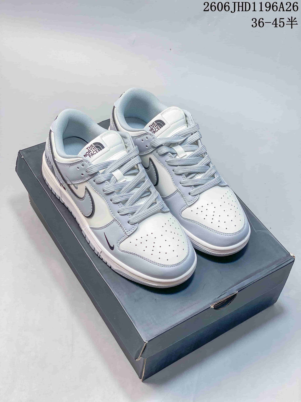 Pair of light gray and white low-top sneakers with pale laces and dark outlined swoosh details.