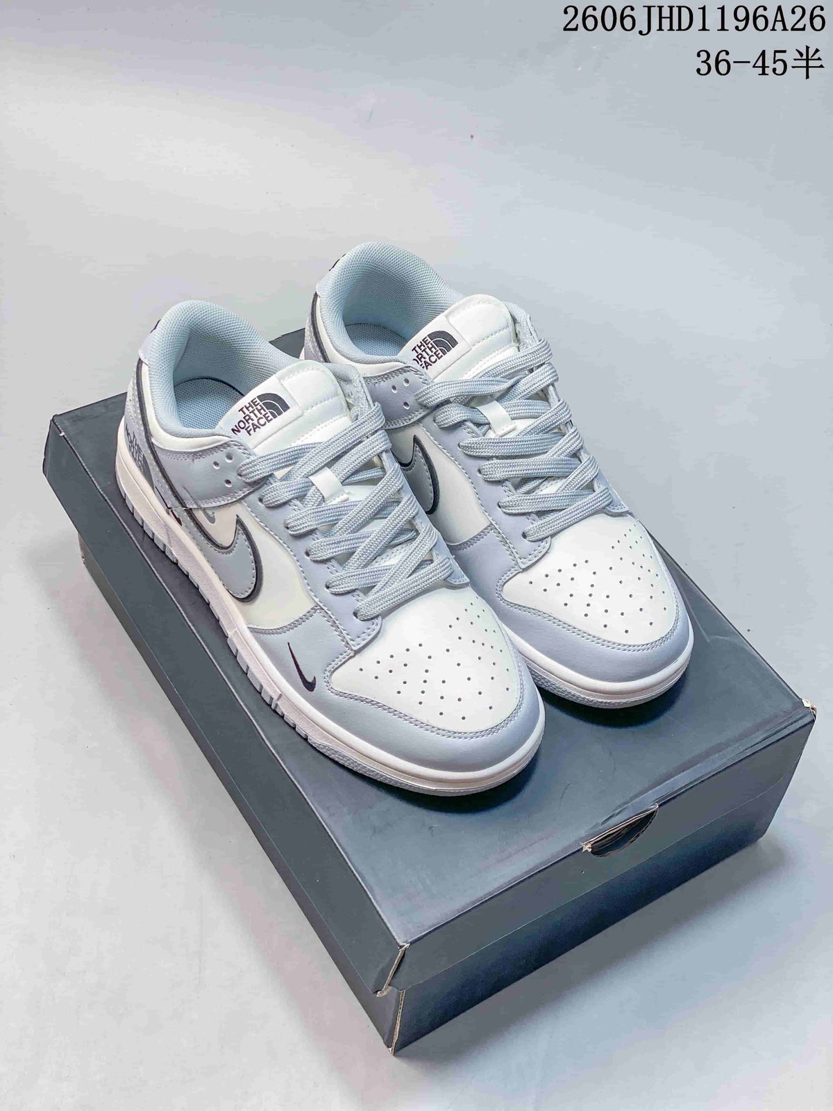 Pair of light gray and white low-top sneakers with pale laces and dark outlined swoosh details.