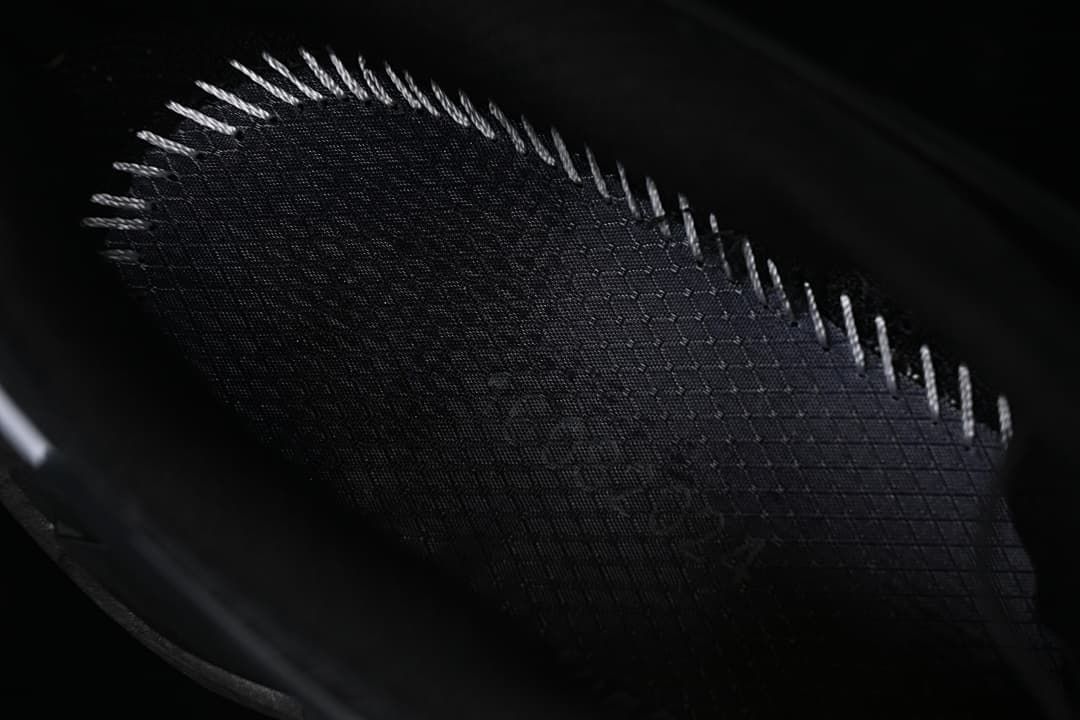 Close-up of the dark textured shoe upper and stitching.