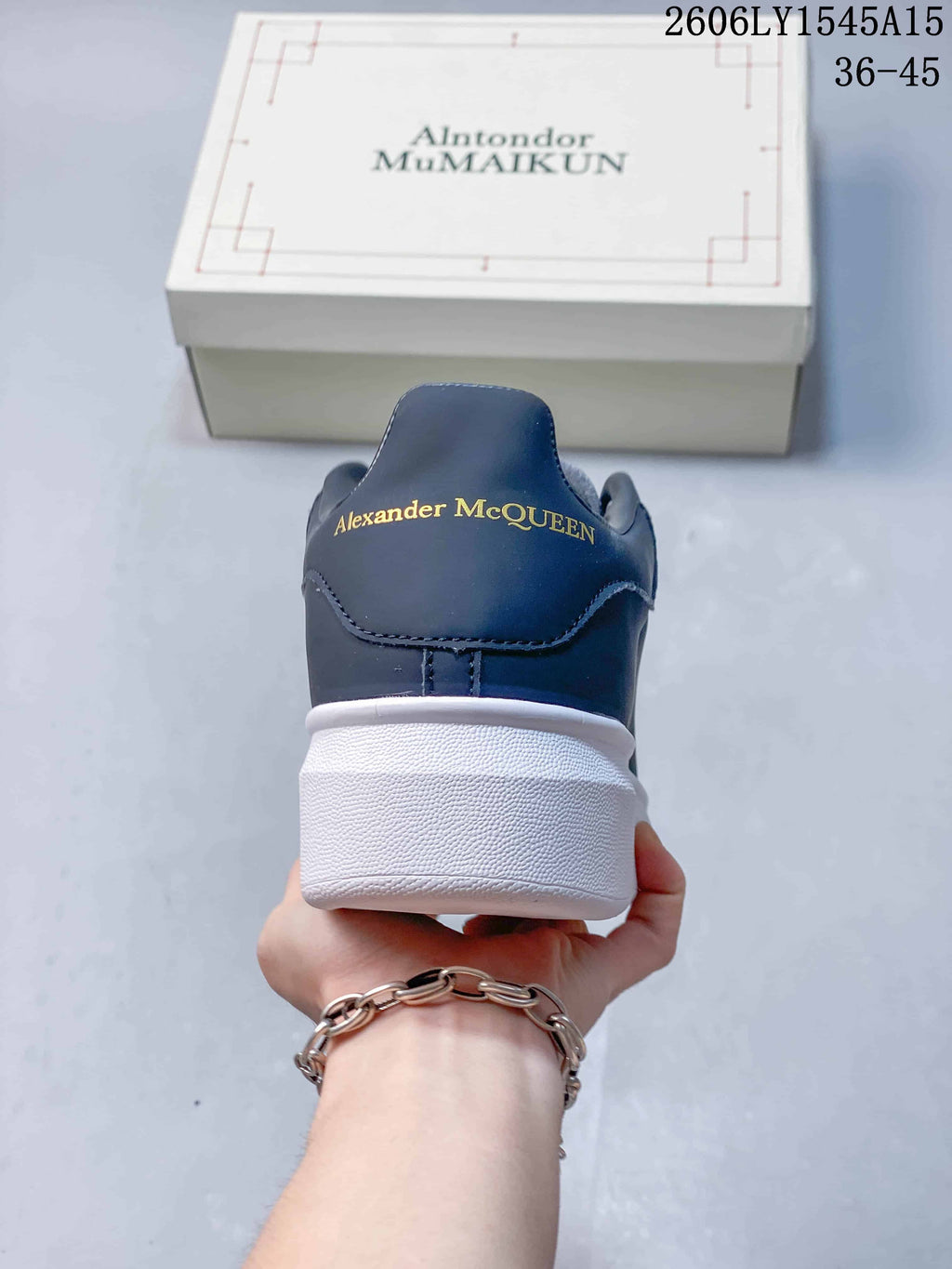 Rear view of a navy sneaker with gold-tone Alexander McQueen lettering and a thick white sole.
