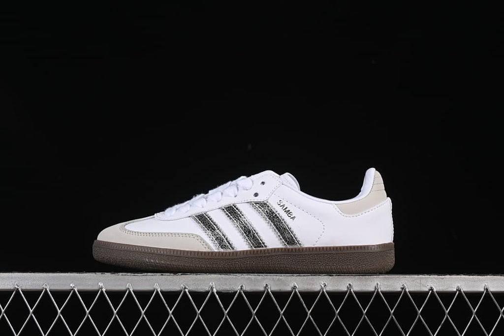 Side view of a white adidas Samba OG sneaker with metallic silver stripes and a dark brown sole