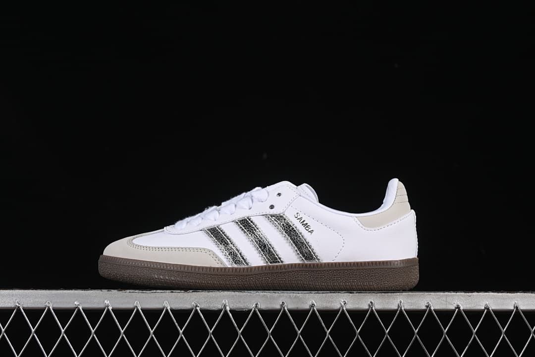 Side view of a white adidas Samba OG sneaker with metallic silver stripes and a dark brown sole