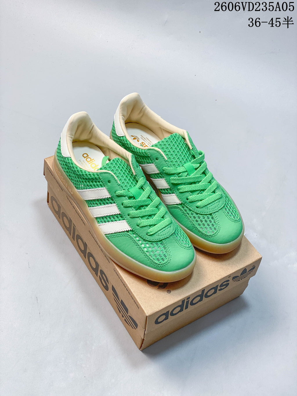 Green adidas Samba low-top sneakers with white stripes and gum-colored soles, shown from above on a shoebox.