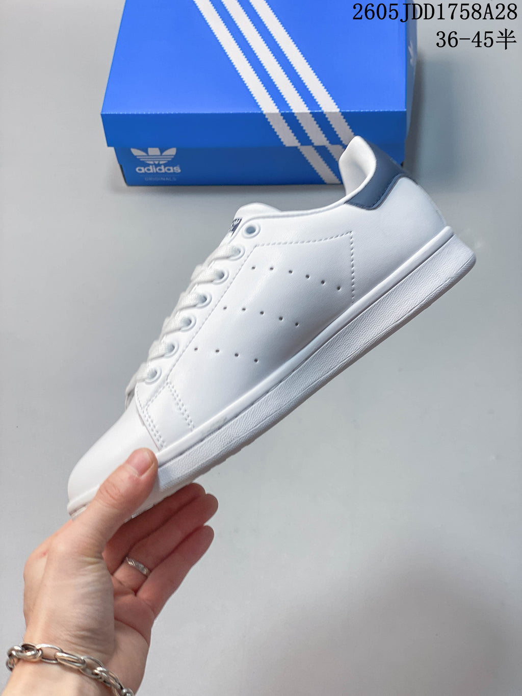 Side view of a white low-top sneaker with perforated panels and a dark blue heel tab.