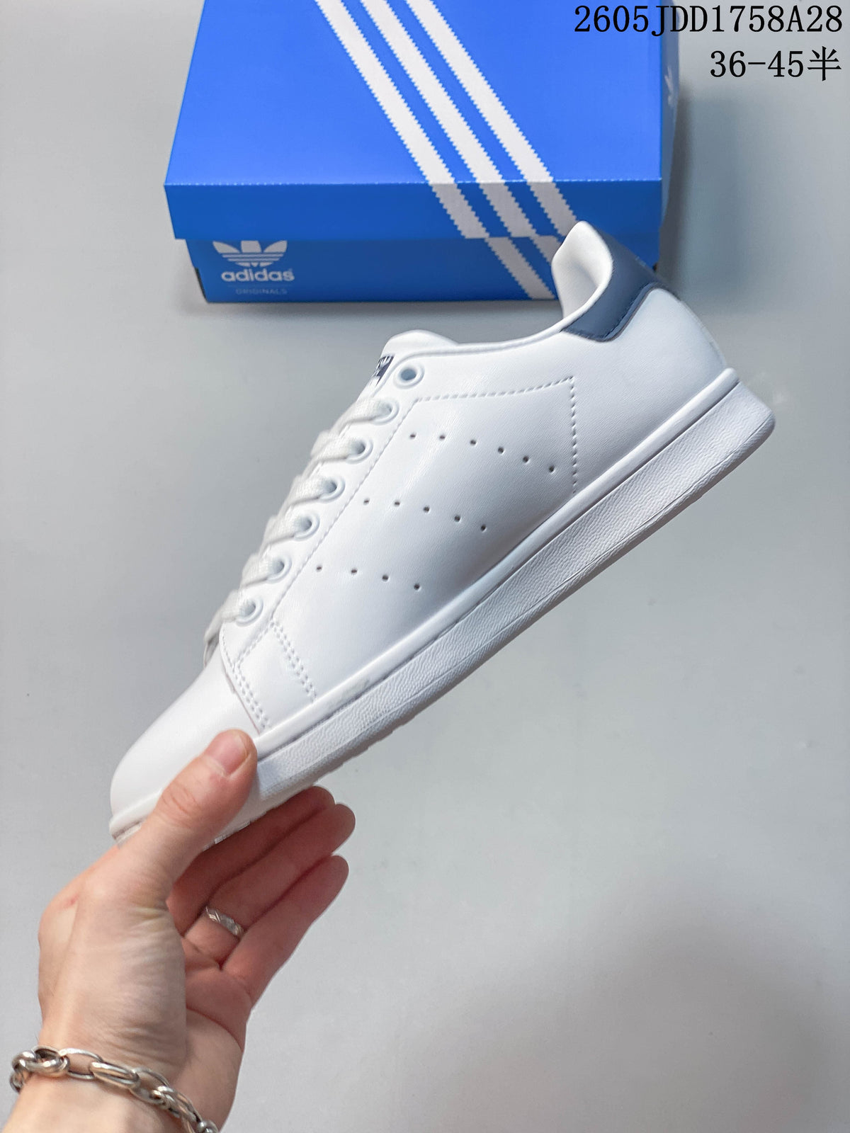 Side view of a white low-top sneaker with perforated panels and a dark blue heel tab.