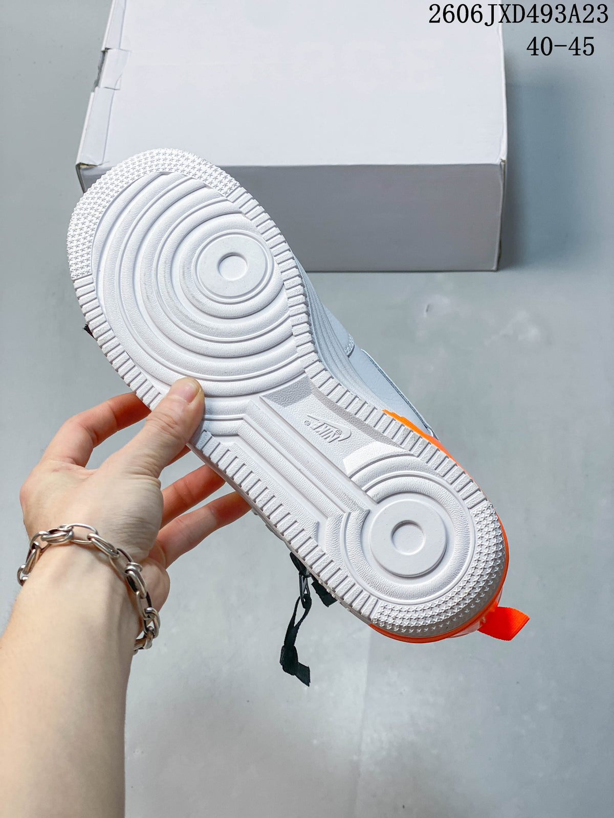 View of the white outsole with circular tread patterns and orange accents