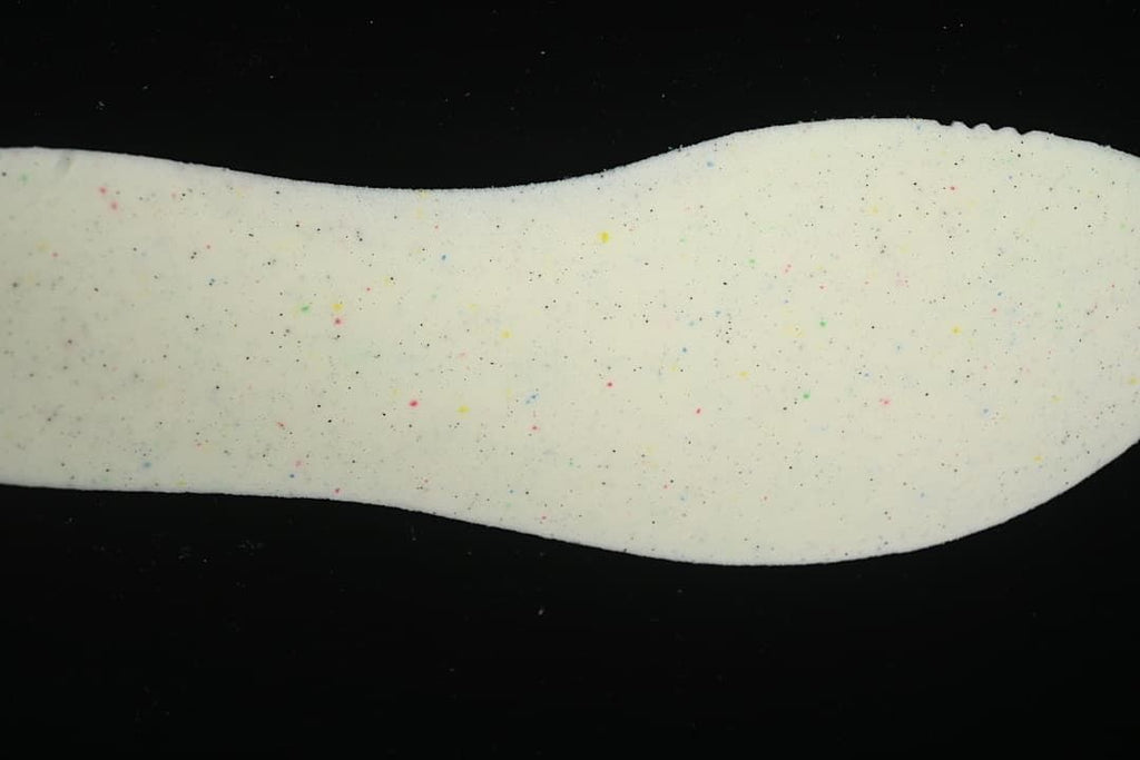 Close-up of a light-colored foam shoe component with multicolor flecks